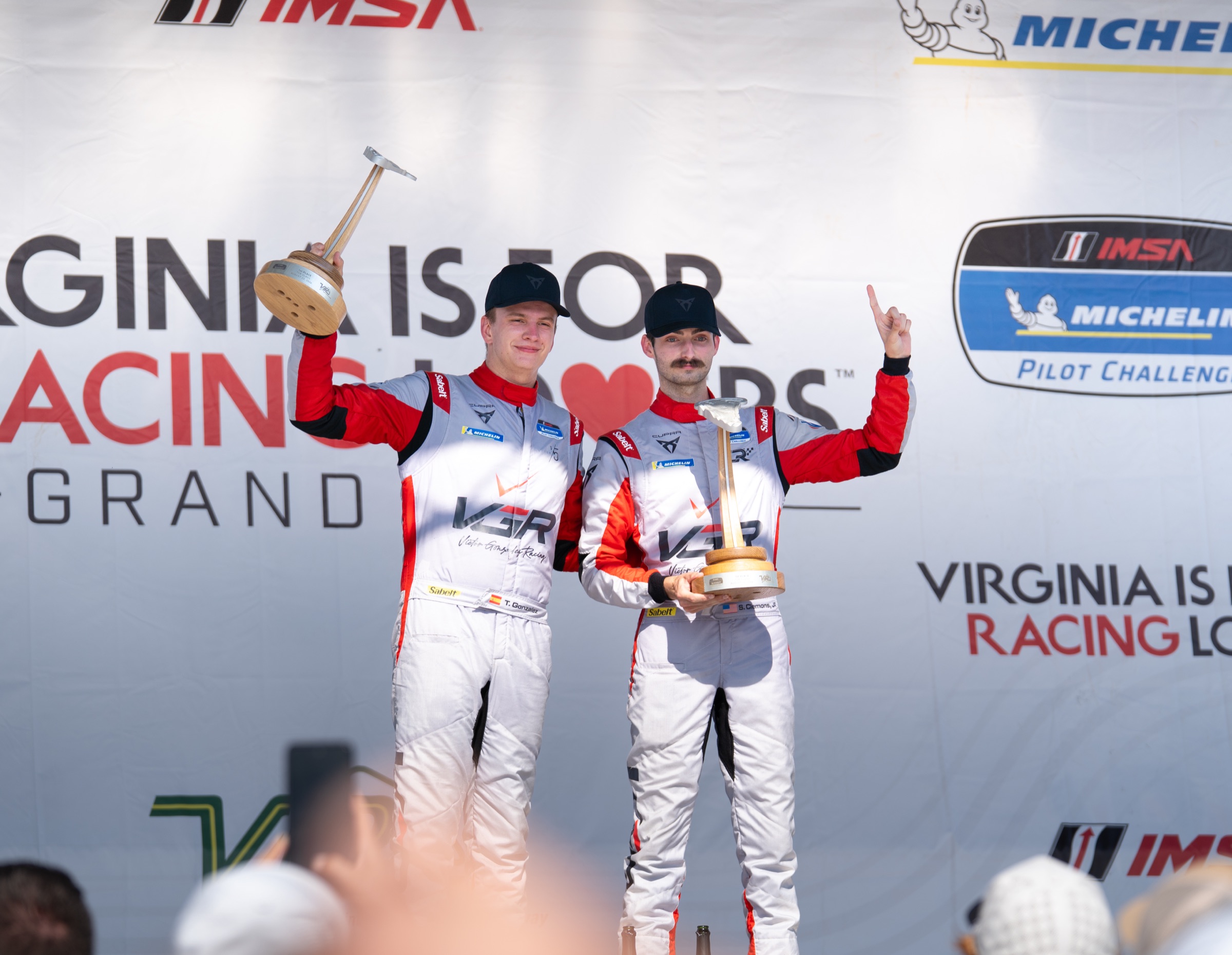 VGR No. 99 drivers hold their VIR winner trophies on the podium